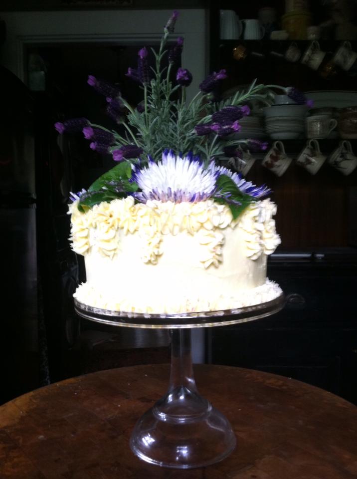 fancy white cake with tall, elaborate flower arrnagement on top